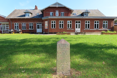 Ungdomshøjskolen ved Ribe startede som efterskole for unge, dansksindede sønderjyder. Grænsesten nr. 2 står i haven. Den stod oprindeligt ved Sprækbro og Grænsegrøften syd for Vester Vedsted og markerede grænsen fra 1864 til 1920. Foto: Charlotte Lindhard